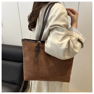 Detail of brown suede tote bag featuring adjustable leather straps with gold metal buckles