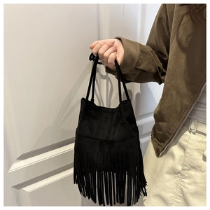 Détail du sac seau bohème en daim noir avec de longues franges et une fine bandoulière