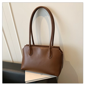 Detail view of a brown minimalist tote bag side profile on a white book display