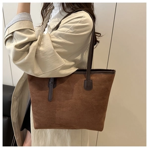 Sac cabas en daim marron avec bandoulière marron foncé porté sur un manteau beige