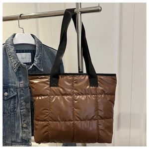 Detail einer braun gesteppten Nylon-Handtasche mit schwarzen Textilgriffen und Ziernähten