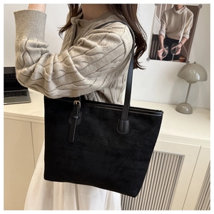 Détail du sac cabas en daim noir avec boucle dorée et texture mate portée à l'épaule