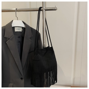 Gros plan du sac seau bohème noir avec de longues franges suspendu à un cintre