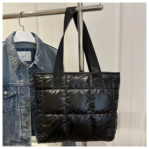 Detail der schwarzen gesteppten Puffer-Tasche aus glänzendem Nylon am Kleiderbügel