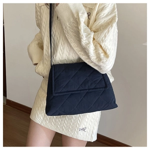 Detail of dark blue quilted crossbody bag with rhombic stitching on soft fabric