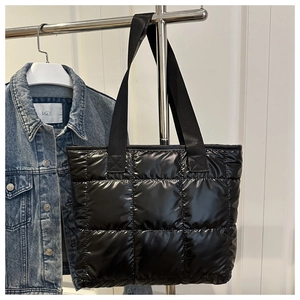 Detailansicht der schwarzen gesteppten Puffer-Handtasche mit breiten Nylon-Tragegriffen