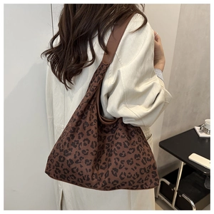 Detail view of large leopard print tote bag on shoulder showing soft fabric texture