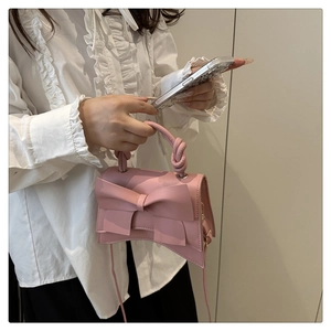 Chic pink leather shoulder bag featuring a large bow and unique twisted woven handle