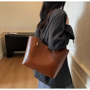 Detail of a brown vintage leather tote bag with elegant gold metal hardware and slim straps
