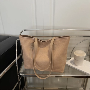 Minimalist beige tote bag with slim shoulder strap on a stylish metal glass trolley