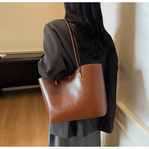 Detail of premium brown oily leather tote bag with elegant thin straps and gold accents