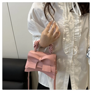 Detail of pink bow handbag with knotted handle and shoulder strap on model