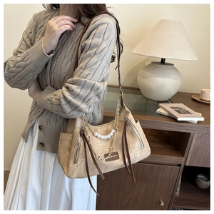 Detail of vintage beige shoulder bag with pearl accents and dual zipper pockets on model