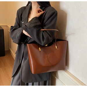 Close-up of vintage brown oily leather tote bag with elegant gold metal hardware details