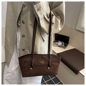 Close-up of brown suede shoulder bag with long straps and stylish fashion metal logo