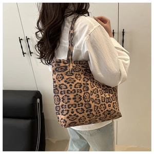 Side view of large leopard print tote bag on shoulder with white shirt and jeans