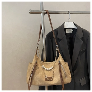 Detail of khaki vintage tote bag featuring decorative gold metal chain and large pearls