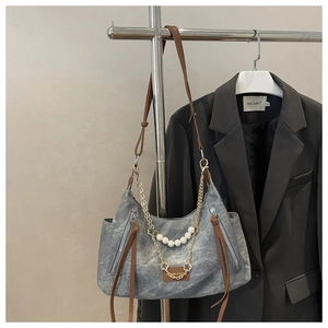 Detail of vintage denim shoulder bag featuring pearl accents and gold chain decoration