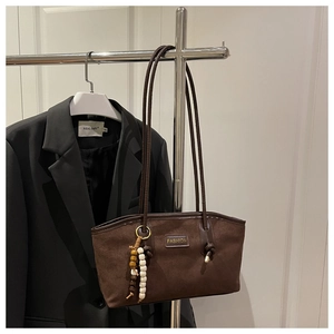 Detail of brown faux suede tote bag featuring fashion label and wooden bead charm accessory