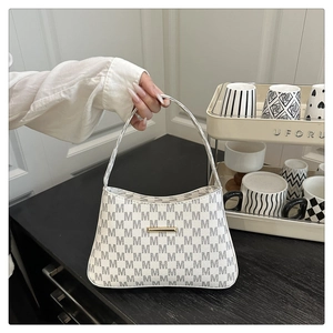 Detail of grey bucket bag with white M-letter print and golden hardware on home shelf