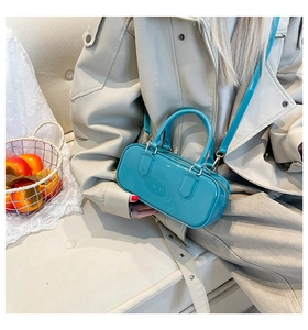 Detail of teal glossy leather handbag with gold hardware and dual handles for women