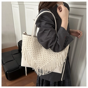 Close-up of bohemian ivory tote bag featuring crochet tassel fringe and faux leather texture