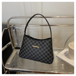 Detail of grey monogram shoulder bag with gold metal trim on a stylish chair