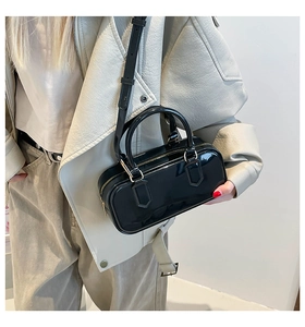 Glossy black patent leather mini handbag with gold-tone hardware on a fashion model