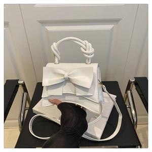 Detail of white fashion handbag showing the big bow decor and knotted rope handle texture