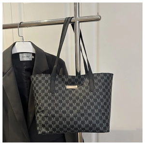 Close-up of gray tote bag featuring all-over M-pattern print and slim black handles