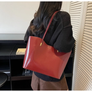 Detailed view of the large glossy wine red tote bag with long straps on a model