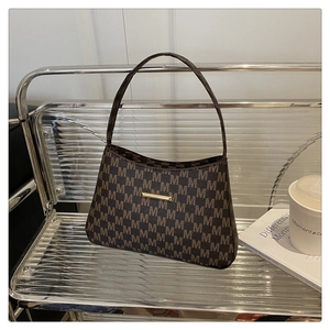 Detail of a dark brown baguette bag with M monogram print and golden metallic buckle