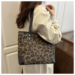 Detail of leopard print tote bag with gold metal logo and black leather straps