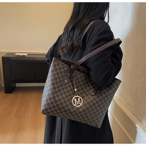 Detail of large monogram tote bag with metallic M-logo charm and stylish shoulder strap