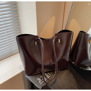 Detailed view of deep brown glossy tote bag with long straps and gold hardware