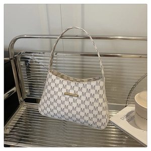 Detail of minimalist cream bucket bag featuring black M prints and gold metal accents