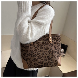 Detail of leopard print tote bag with leather reinforced corners and gold metal nameplate