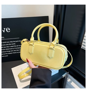 Detail of yellow patent leather shoulder bag showing glossy texture and handles