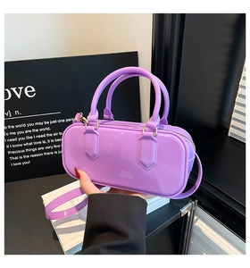 Detail of purple glossy cylinder jelly bag featuring gold hardware and dual handles