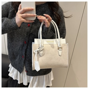 Detail of cream white leather and suede patchwork bag with golden fashion logo lettering