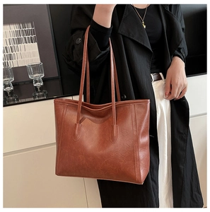 Detailed view of brown leather tote bag showing grainy texture and reinforced handles