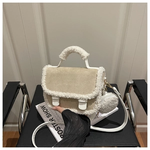 Dettaglio borsa a sella scamosciata beige con bordo in pile teddy su sedia di pelle