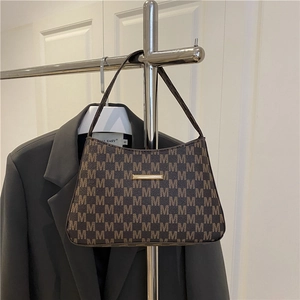 Brown bucket bag with M-letter print and gold metal buckle shown on a suit background