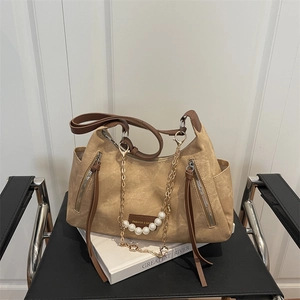 Retro khaki large tote bag with brown straps and pearl chain charm on a black chair