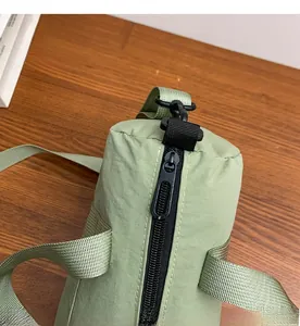 Detail of smooth zipper closure on light green nylon cylinder crossbody bag