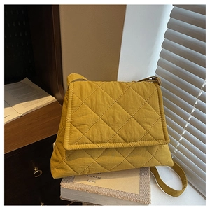 Detail of yellow quilted crossbody bag with soft texture resting on vintage books