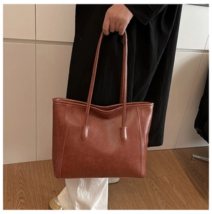 Detail of vintage brown tote bag in vegan leather being held by a model in a modern room