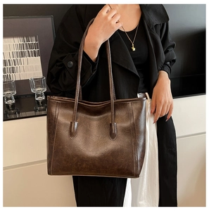Close-up of deep brown oil wax leather texture and slim straps on a large tote bag