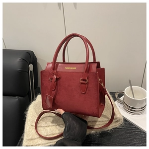 Detail of red leather crossbody bag with FASHION & BAGS text on a textured surface