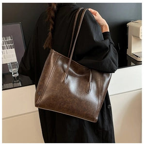 Dark brown vintage tote bag in oil-waxed leather texture shown on a female model